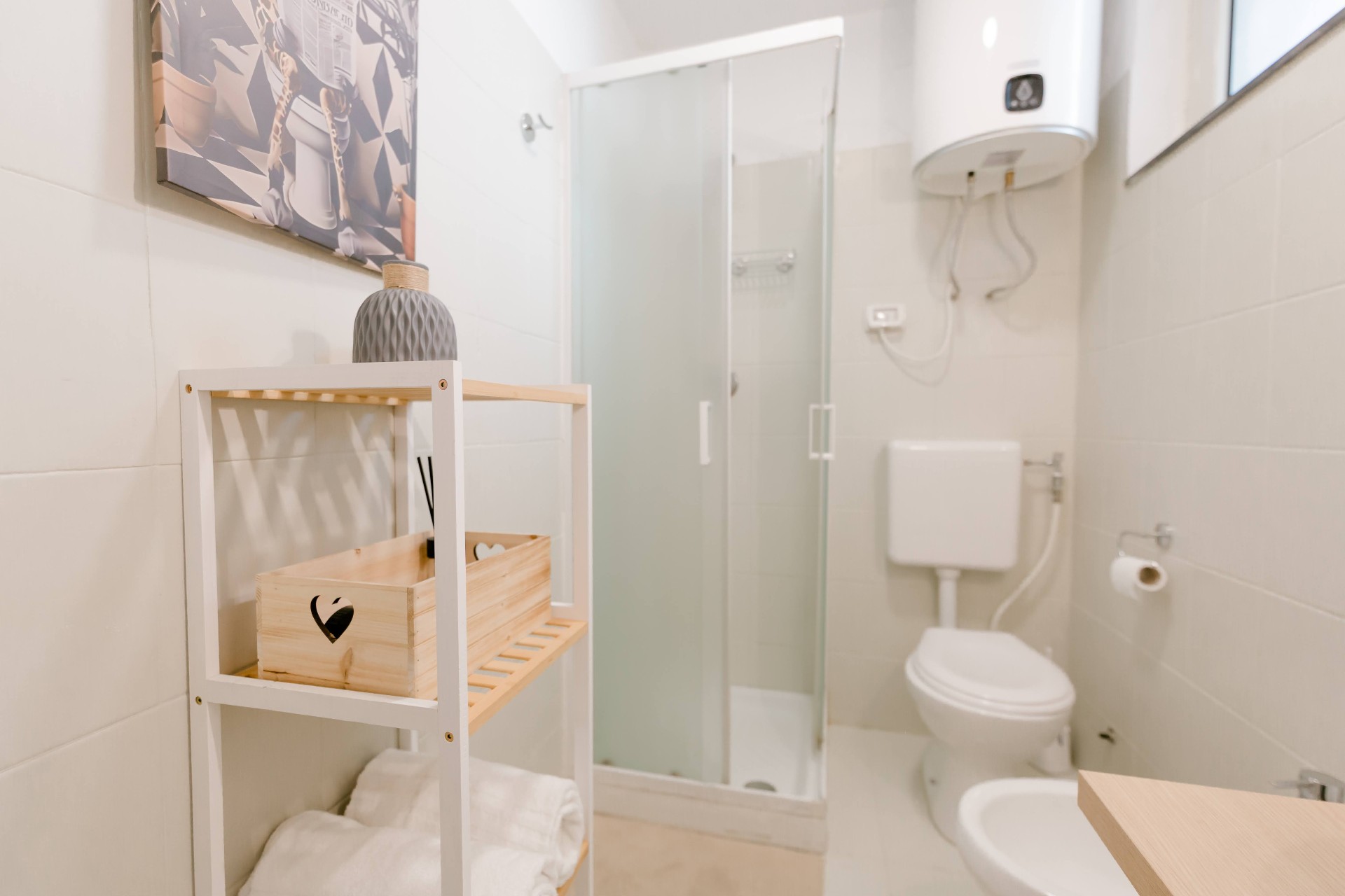 Bagno di Bedda Matri con doccia in cristallo, sanitari sospesi, scaldabagno elettrico e arredi in legno chiaro