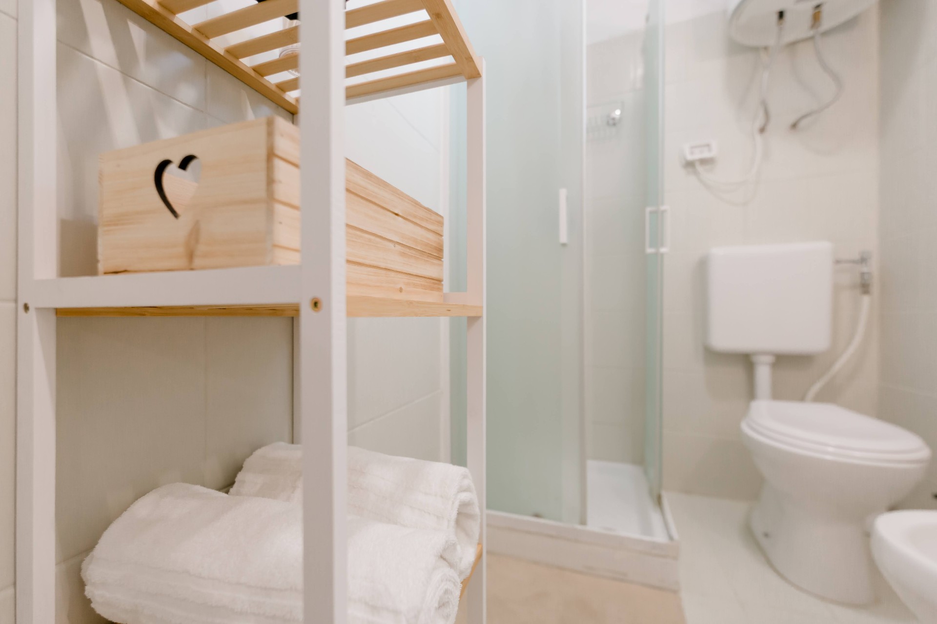 Box doccia in cristallo satinato e mensola in legno con asciugamani in spugna bianca offerti dalla casa