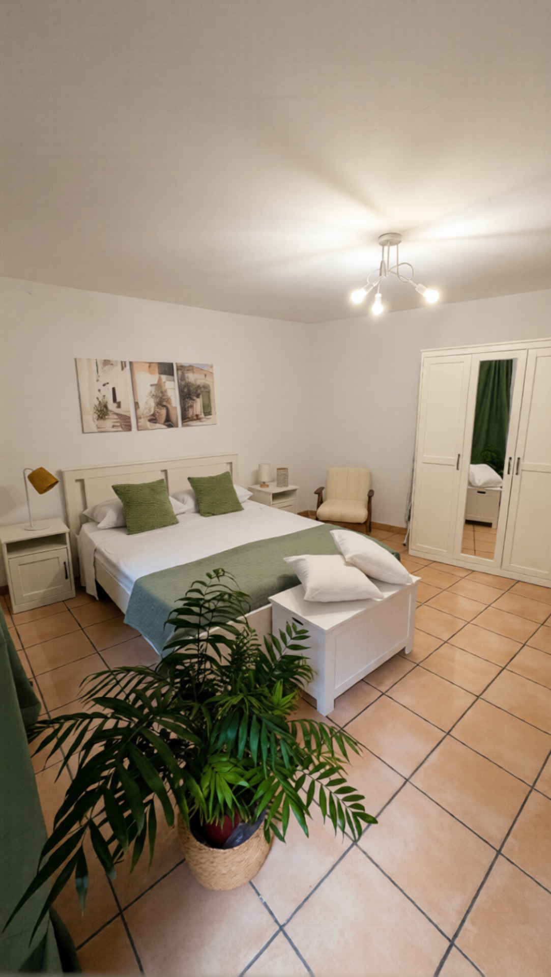 Camera matrimoniale principale con letto king size, biancheria in cotone bianco, plaid verde e armadio a tre ante con specchio