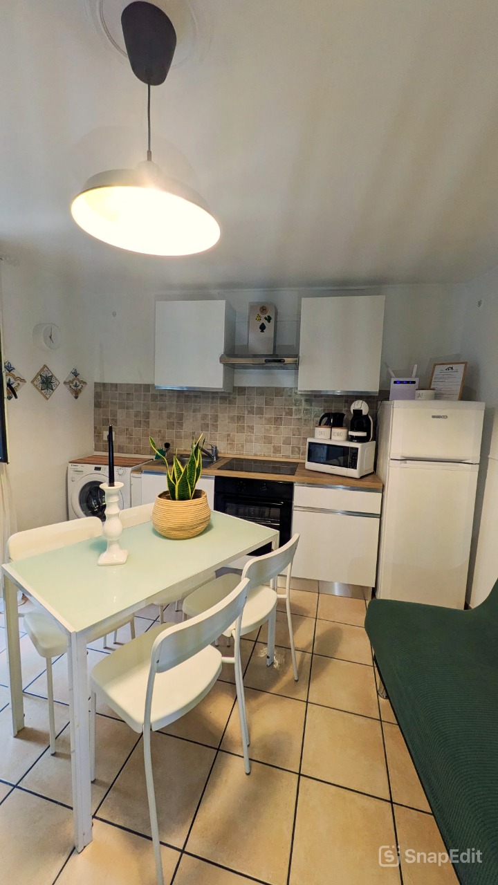 Cucina attrezzata di Bedda Matri con piano cottura a induzione, forno, microonde, frigorifero, lavatrice e tavolo da pranzo per quattro persone