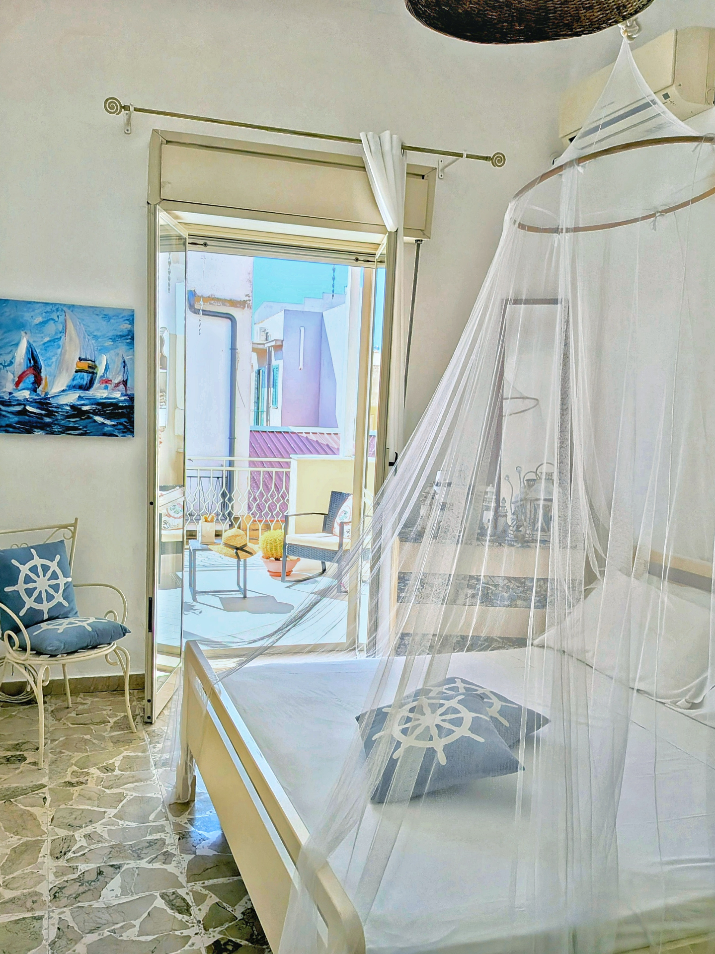 Bedroom with mosquito net and view of the private terrace at Libeccio House in Avola